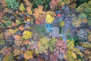 An aerial view of a house surrounded by autumn-colored trees. - Secluded•Hot tub•Fire pit•Pet-friendly Cabin (Shenandoah)
