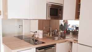 Una cuina moderna amb armaris blancs, electrodomèstics d'acer inoxidable, microones, rentaplatets i un rentamans.
