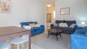 En moderne stue med en blå sofa, en grå sofa, et træsofabord og en hvid stol.