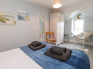 A bedroom with a bed, a chair, a wardrobe, and a window with a crescent moon decoration. - Bryn Tirion (Pwllheli)