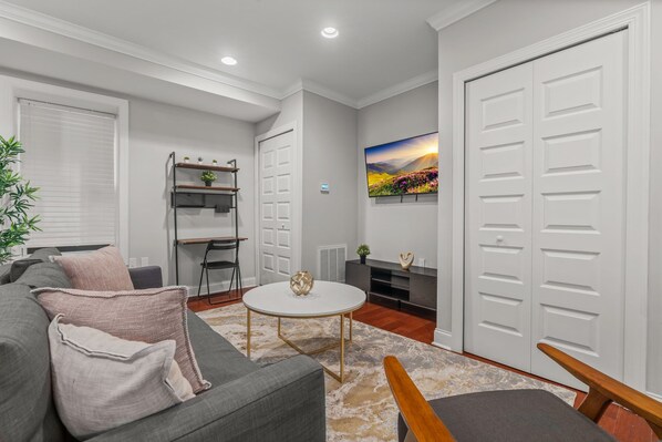 A modern living room with a grey sofa, a coffee table, and a TV mounted on the wall.