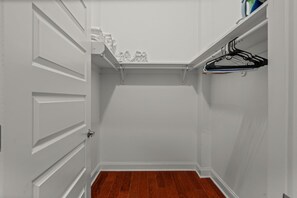 A closet with white doors and a wooden floor.