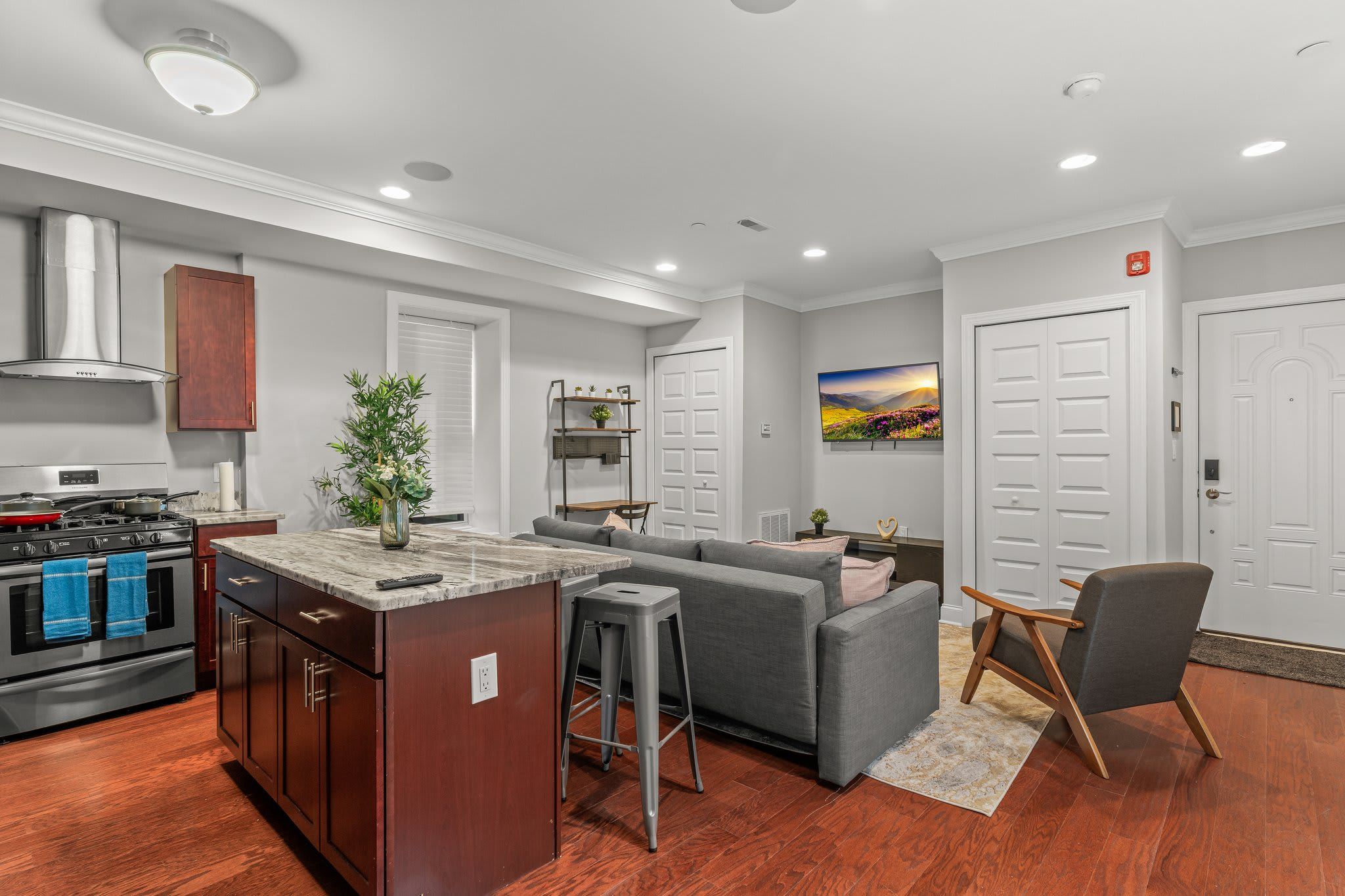 A modern kitchen with a central island, built-in oven, and stainless steel range hood.