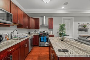 A modern kitchen with wooden cabinets, stainless steel appliances, and a marble countertop.