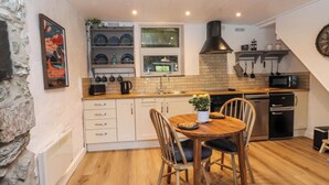A compact kitchen with a wooden dining table, chairs, and a built-in oven.