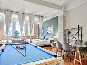 Ein Hotelzimmer mit Billardtisch, einem Bett, einem Schreibtisch und einem Stuhl.