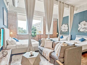 Habitación de hotel con una cama grande, un sofá, una mesita de café y vistas al exterior.