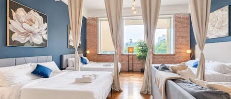 A hotel room with two beds, a brick wall, and a large window.
