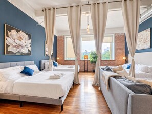 A hotel room with two beds, a brick wall, and a large window.