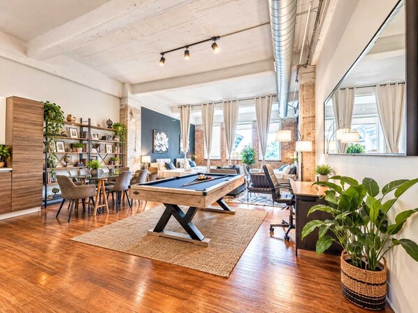 A spacious living area with a pool table, seating, and a bookshelf.