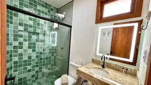 Ein Badezimmer mit Duschkabine aus Glas, einer weißen Toilette und einem Waschbecken mit Spiegel darüber.