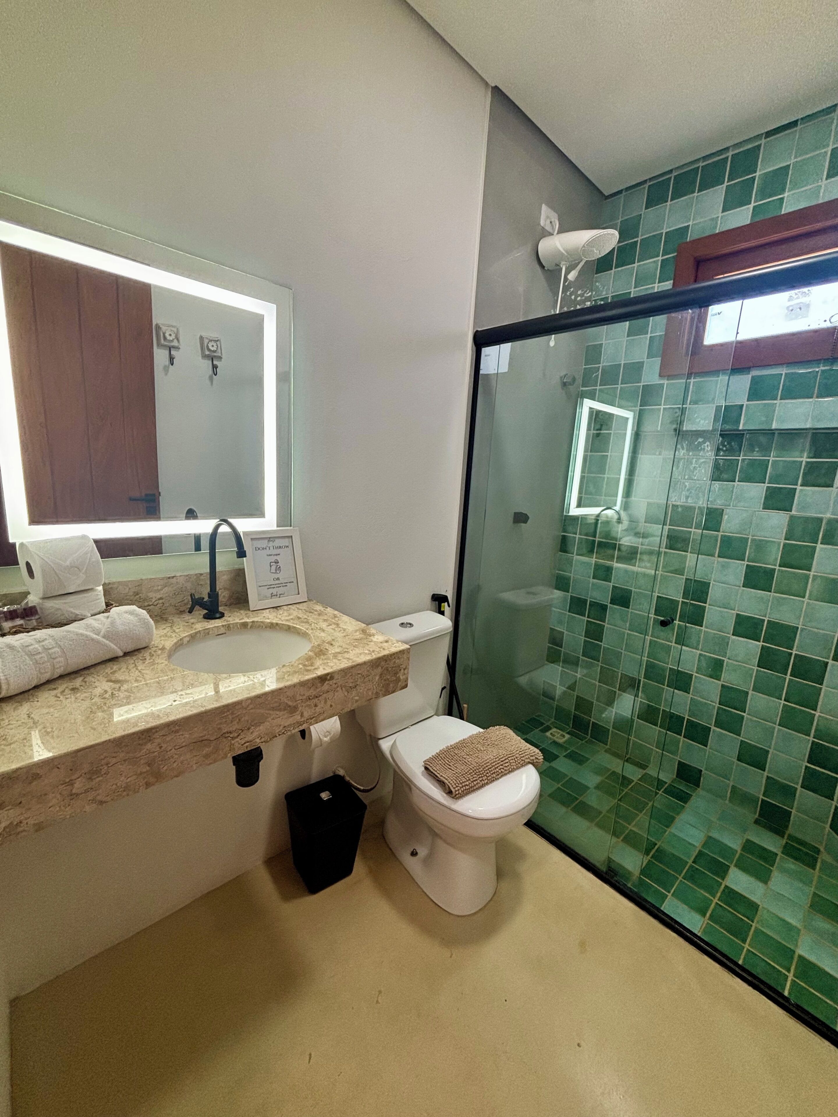 Un baño con lavamanos, espejo, inodoro y zona de ducha.