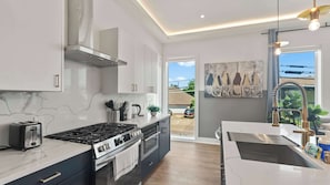 A modern kitchen with a gas stove, oven, and a large window.