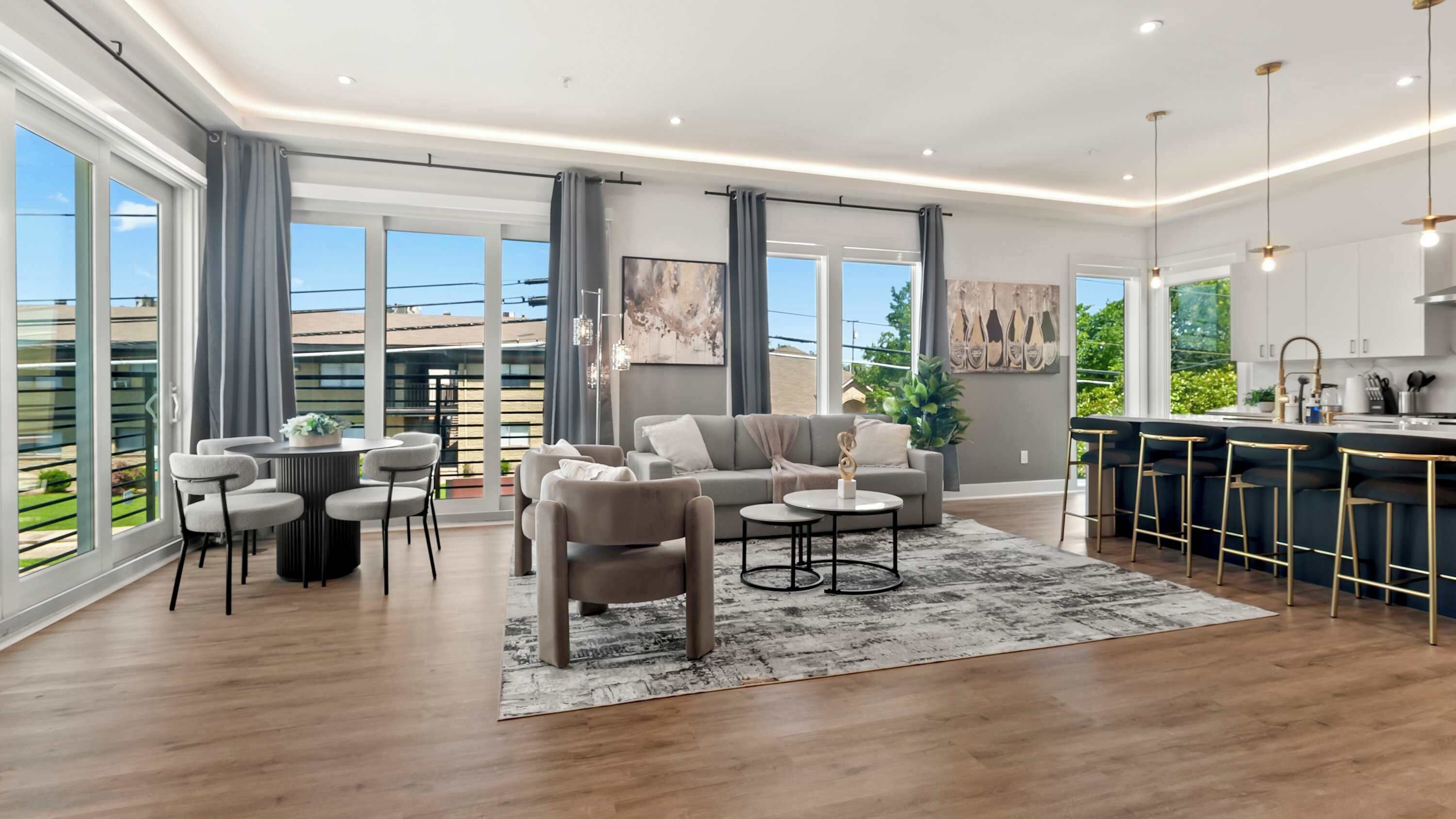A modern living room with a sofa, chairs, a coffee table, and a kitchen area with bar stools.