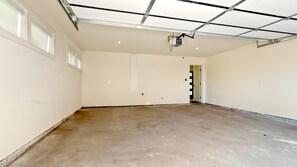 Um quarto espaçoso e vazio, com pé direito alto, janelas grandes e uma porta visível que dá para outra área.