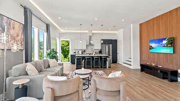 A modern living room with a sofa, chairs, a coffee table, and a TV mounted on the wall.
