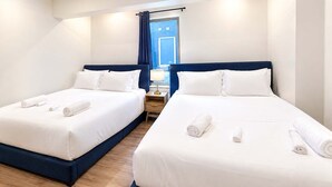 Een hotelkamer met twee bedden, elk voorzien van witte lakens en opgerolde handdoeken.