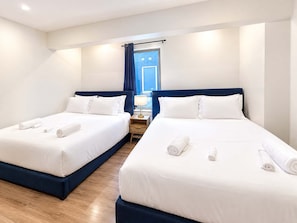 A hotel room with two beds, each with white linens and rolled towels.