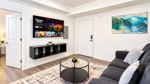 Een moderne woonkamer met een flatscreen televisie, een bank, een salontafel en een vloerkleed.