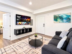 A modern living room with a flat-screen TV, a sofa, a coffee table, and a rug.