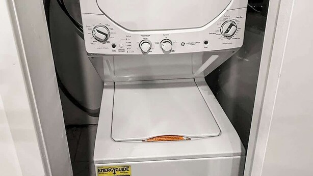 Voorzijde van een was- en droogcombinatie met bedieningsknoppen, een startknop en een label dat de energie-efficiëntie aangeeft.