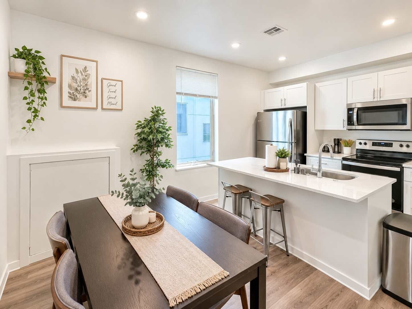 Una cocina moderna con armarios blancos, electrodomésticos de acero inoxidable y una isla central con taburetes de bar.