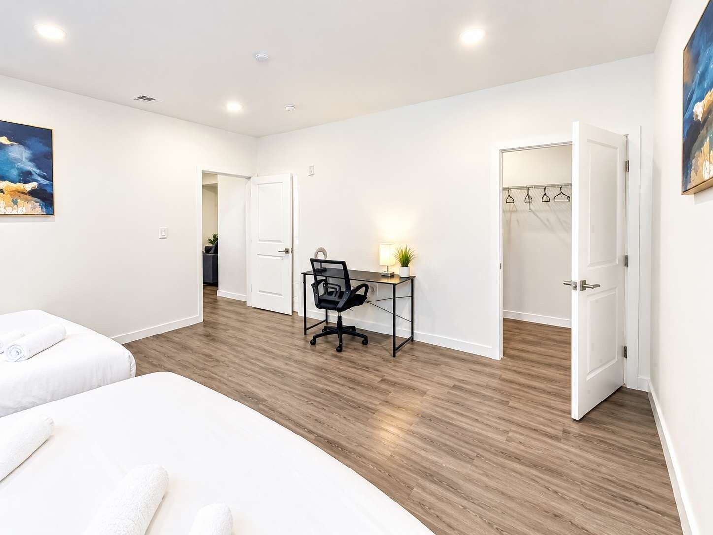 Habitación de hotel con cama, escritorio, silla y armario con perchas.