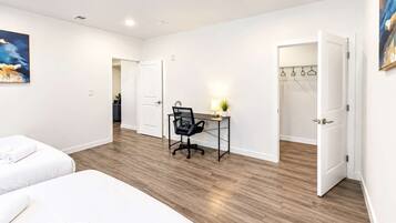 Habitación de hotel con cama, escritorio, silla y armario con perchas.