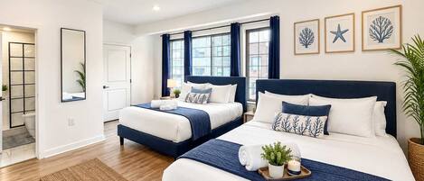 Habitación de hotel con dos camas, un ventanal grande y vistas a la ciudad.