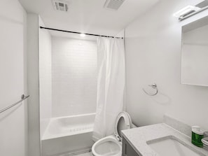 Un baño con una bañera blanca, un inodoro, un lavamanos y una cortina de ducha.