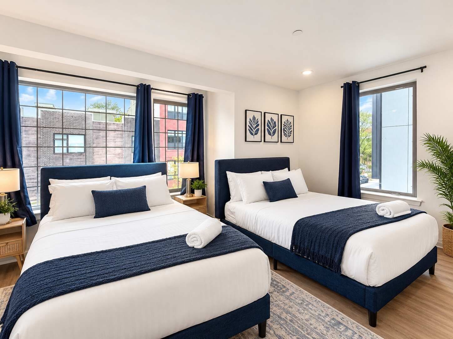 Ein Hotelzimmer mit zwei Betten, einem großen Fenster und Blick auf die Stadt.