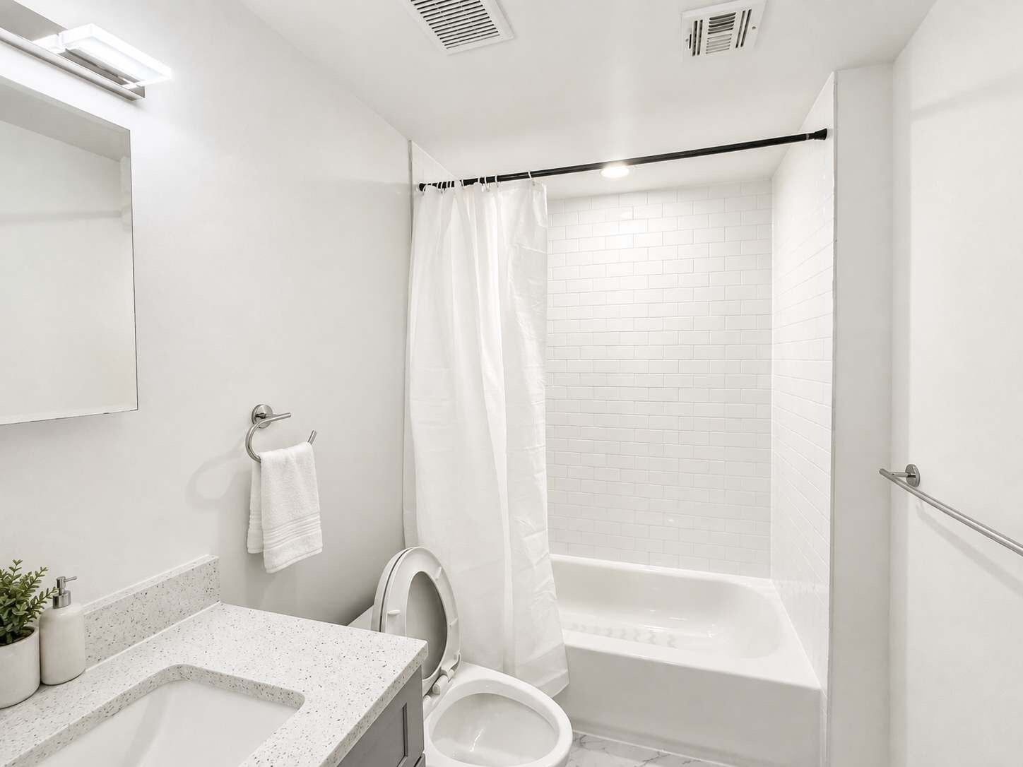 Un baño moderno con lavamanos, inodoro y bañera blancos.