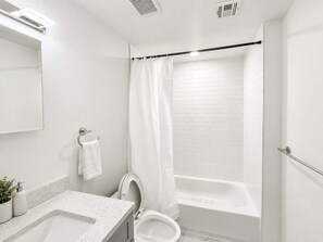 A modern bathroom with a white sink, toilet, and bathtub. - Sleek Contemporary 2BD | Sleeps 6 | NoLib (Philadelphia)