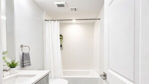 A modern bathroom with a toilet, sink, and shower area. - Inviting 2BD | Sleeps 6 | Northern Liberties (Philadelphia)
