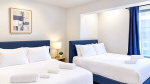 A hotel room with two beds, a bedside table with a lamp, and a window with curtains. - Inviting 2BD | Sleeps 6 | Northern Liberties (Philadelphia)