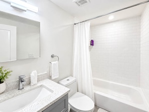 A modern bathroom with a white sink, toilet, and bathtub.