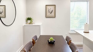 A conference room with a long table, four chairs, a potted plant, and framed artwork on the walls. - Inviting 2BD | Sleeps 6 | Northern Liberties (Philadelphia)