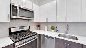 Une cuisine moderne dotée d’appareils électroménagers en acier inoxydable, de meubles blancs et d’un lave-vaisselle encastré.