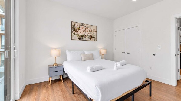 Une chambre d’hôtel avec un lit, des tables de chevet, un tableau et une armoire.