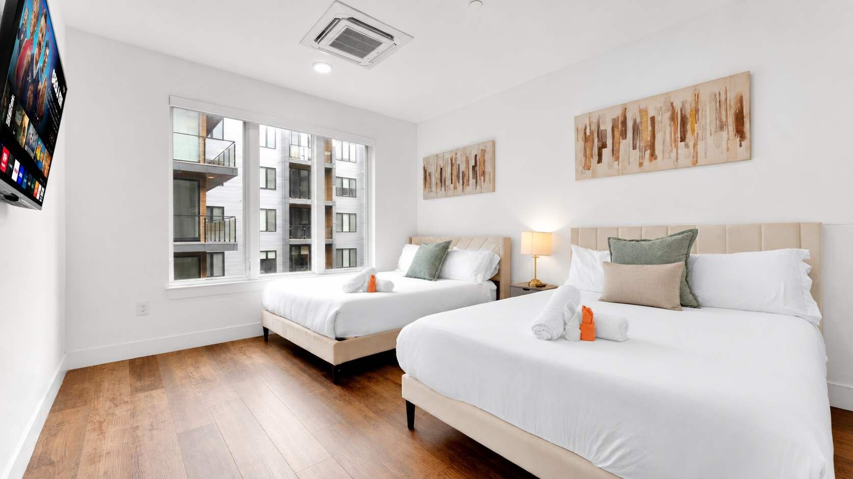 Ein Hotelzimmer mit zwei Betten, einem großen Fenster und Kunstwerken an den Wänden.