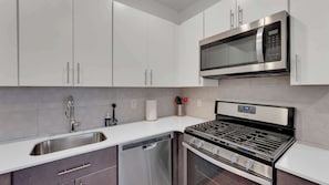 Uma cozinha moderna com eletrodomésticos de aço inoxidável, lava-louças e fogão a gás.