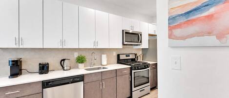 A modern kitchen with white cabinets, stainless steel appliances, and a dishwasher.