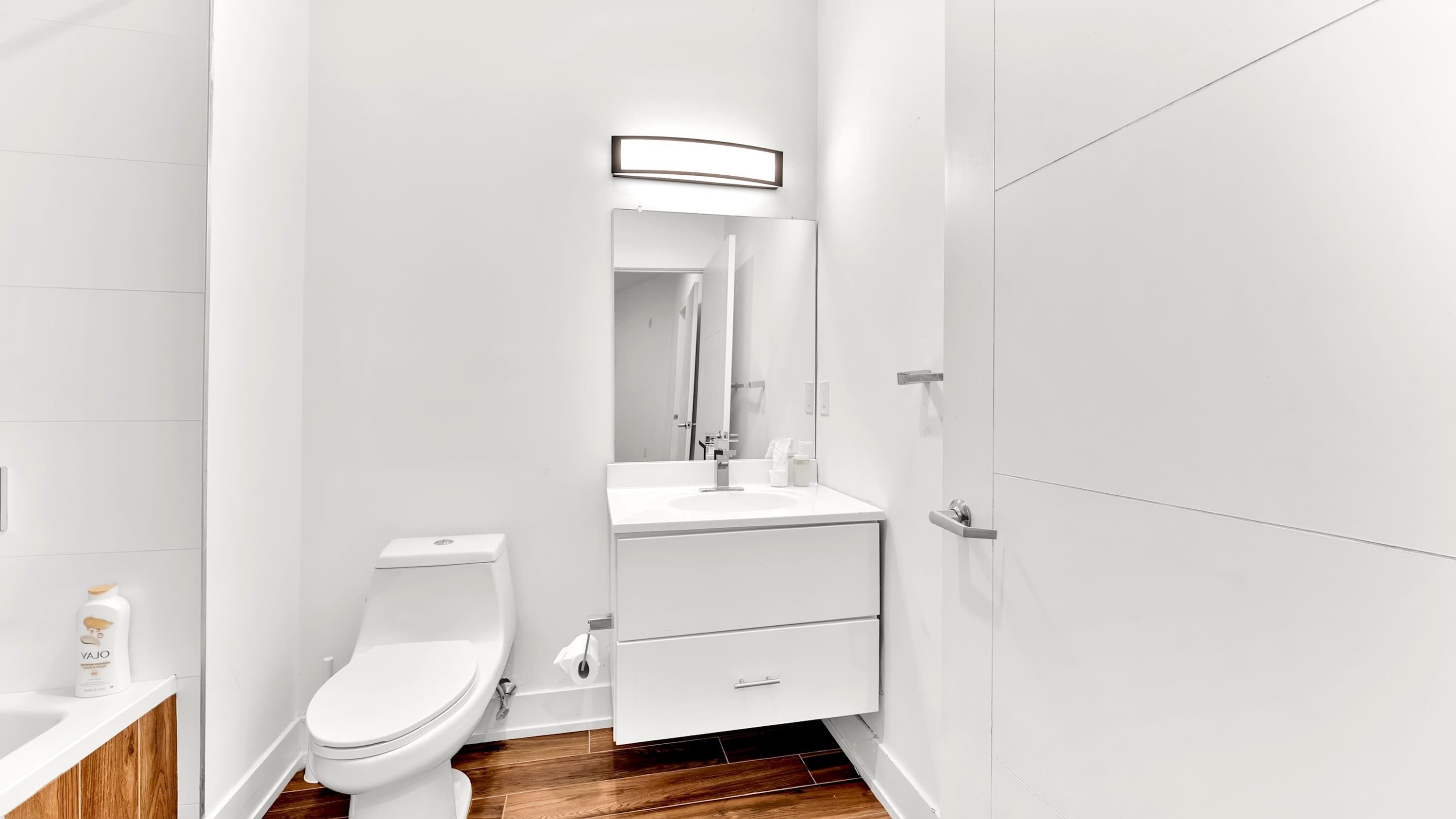 Un baño moderno con inodoro, lavamanos y espejo.