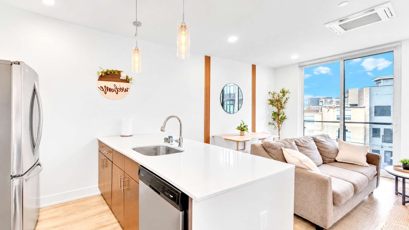 A modern kitchen with a central island, a built-in dishwasher, and a stainless steel refrigerator.