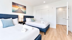 A hotel room with two beds, a nightstand, a painting, and a wardrobe.