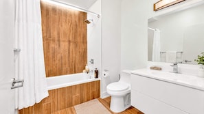A modern bathroom with a wooden bath, white fixtures, and a large mirror.