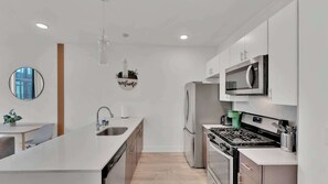 Une cuisine moderne dotée d’un îlot central, d’appareils électroménagers en acier inoxydable et d’un design minimaliste.