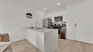 Una cocina moderna con una isla central, electrodomésticos de acero inoxidable y armarios blancos.