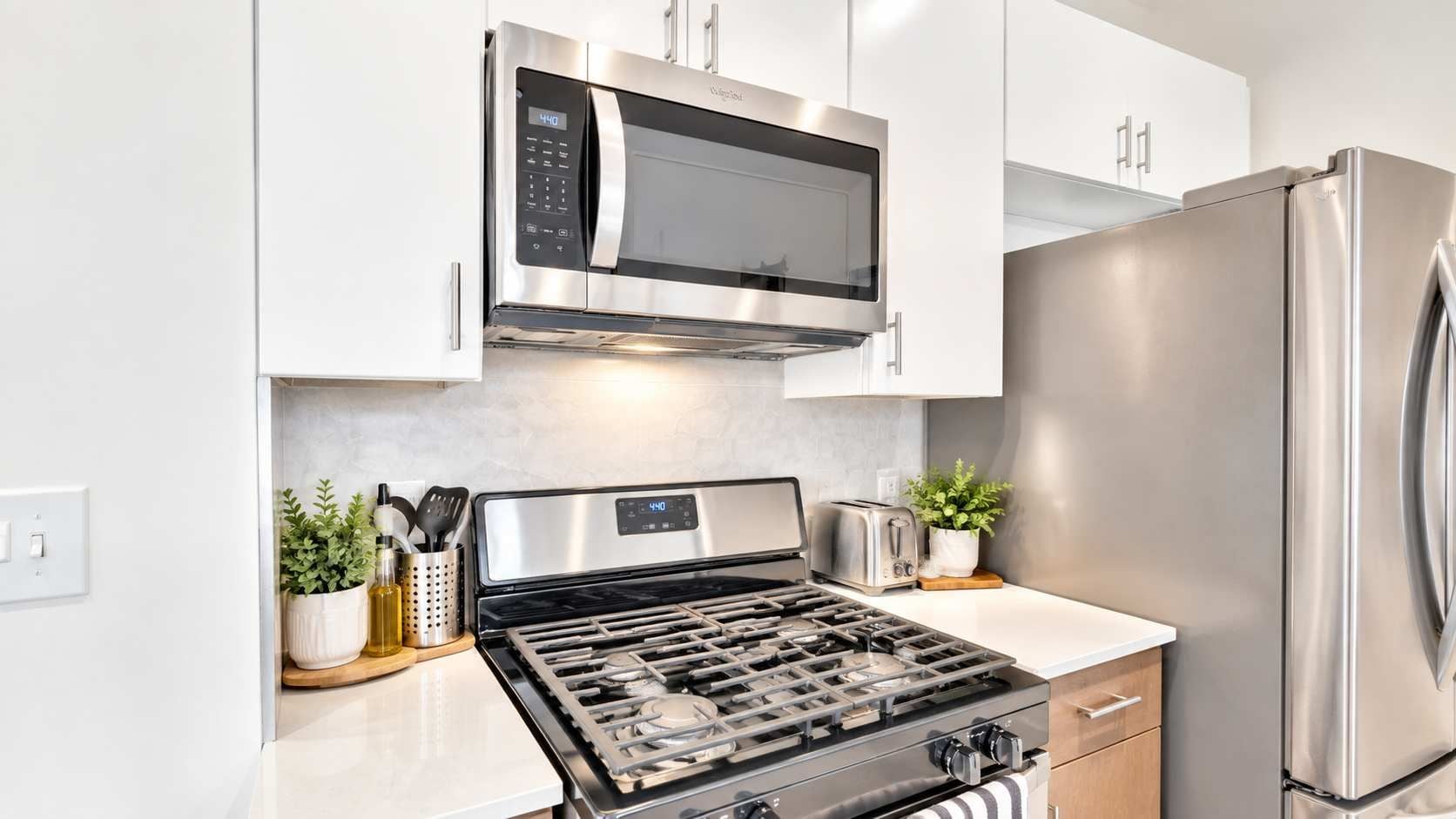 Una cocina moderna con electrodomésticos de acero inoxidable, incluyendo un microondas, estufa y refrigerador.