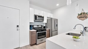 A modern kitchen with white cabinetry, stainless steel appliances, and a white countertop.
